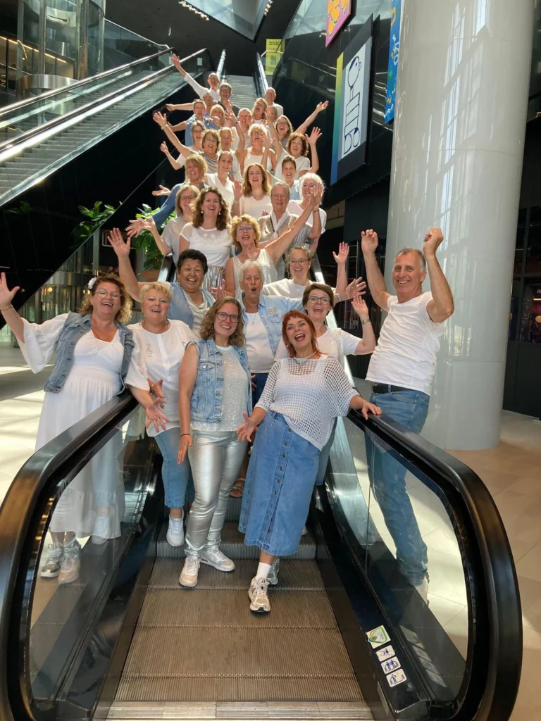 Foto van zwaaiende leden op een roltrap in een winkelcentrum.